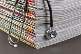 A stethoscope is draped over a stack of medical journals