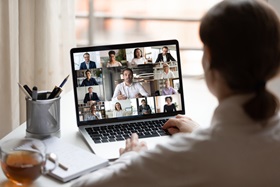 person in front of a laptop with a virtual meeting going on