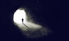 person walking out of a dark tunnel