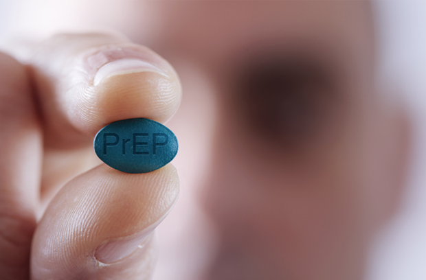 blurry_man_in_background_holds_blue_prEP_pill_for_HIV_prevention