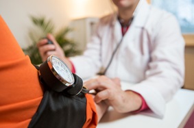 Elderly obese woman having her blood pressure measured by a doctor using a blood pressure cuff