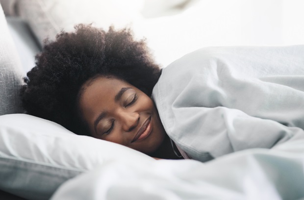 Woman smiling while sleeping under a fluffy blanket
