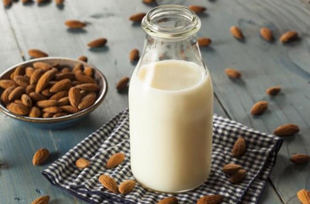 a glass of milk and almonds on a table