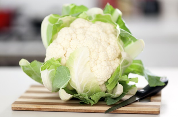 Whole cauliflower on cutting board with knife