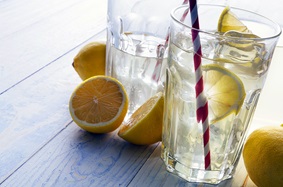 Water with lemon in clear glass with red and white straw