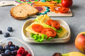 Open-faced tomato, lettuce and cheese sandwich packed in reuable lunch container