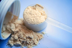 Scoop of protein powder on a blue background