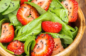 Bowl of strawberry, spinach greens and sesame seeds