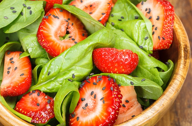Bowl of strawberry, spinach greens and sesame seeds
