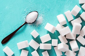 Spoon filled with granulated sugar surrounded by sugar cubes