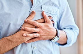 man holding chest heart palpitations 