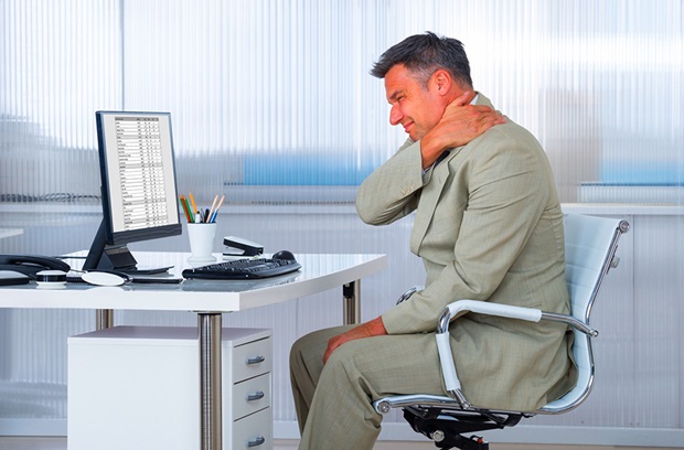 man holding neck while sitting at desk