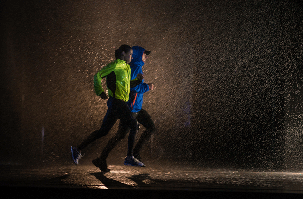 People running in the dark while it's raining