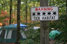 sign warning about ticks in front of a camp site
