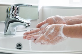 sudsy hands rinsing off in the sink