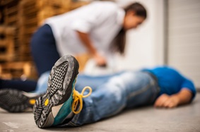 woman helping man who is lying on floor, seemingly unconscious 