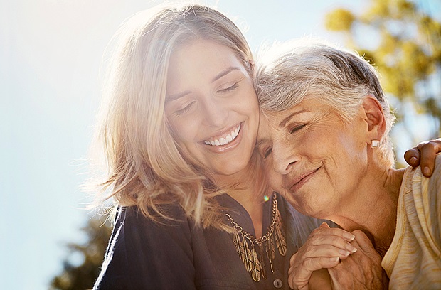 A grandmother hugging her adult granddaughter while smiling