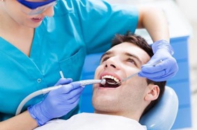 man getting teeth cleaned by dentist