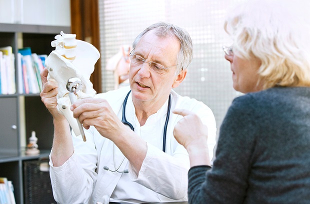 Doctor showing artificial hip model to patient