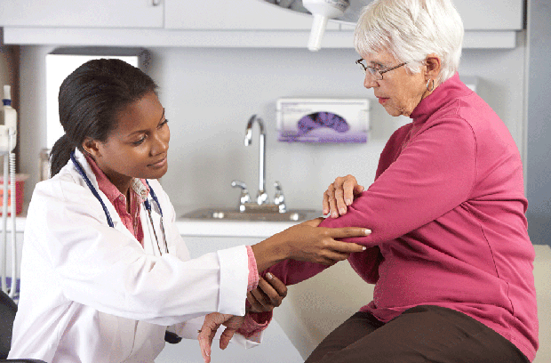 Female doctor inspecting female patient"s elbow