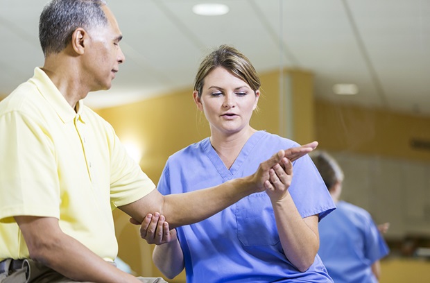 Female nurse examining patient's hand and wrist