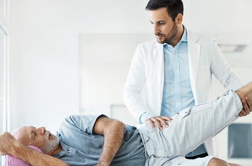 Doctor examining a hip of a senior gentleman during an appointment.