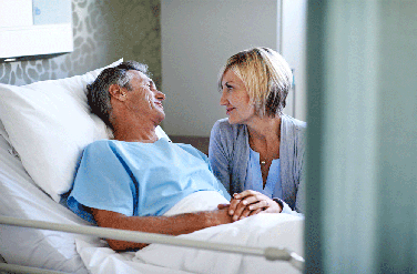 Male patient in bed smiling at wife