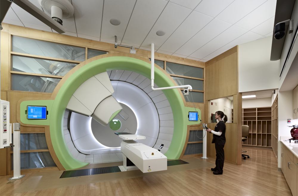 A nurse stands in a clinical space and prepares proton therapy. 